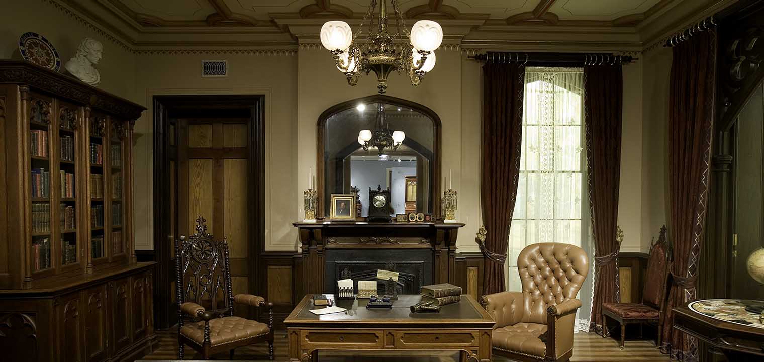 The desk in the Gothic Revival Library in front of the fireplace and looking glass