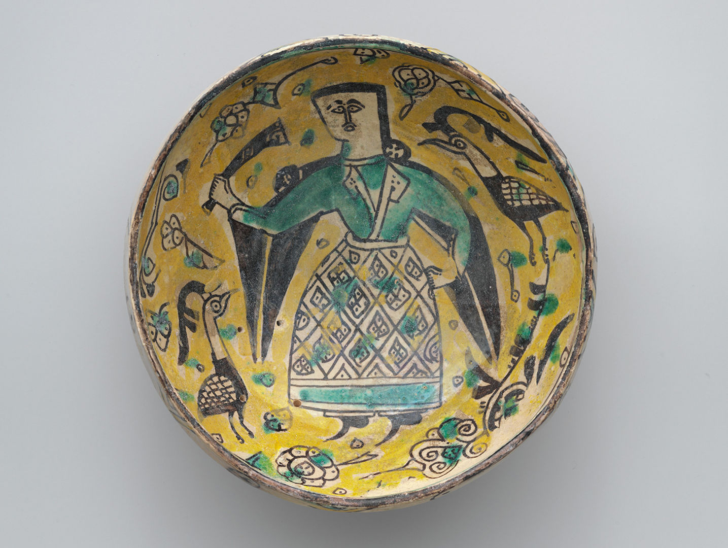Yellow earthenware bowl with figure and birds decorating the surface