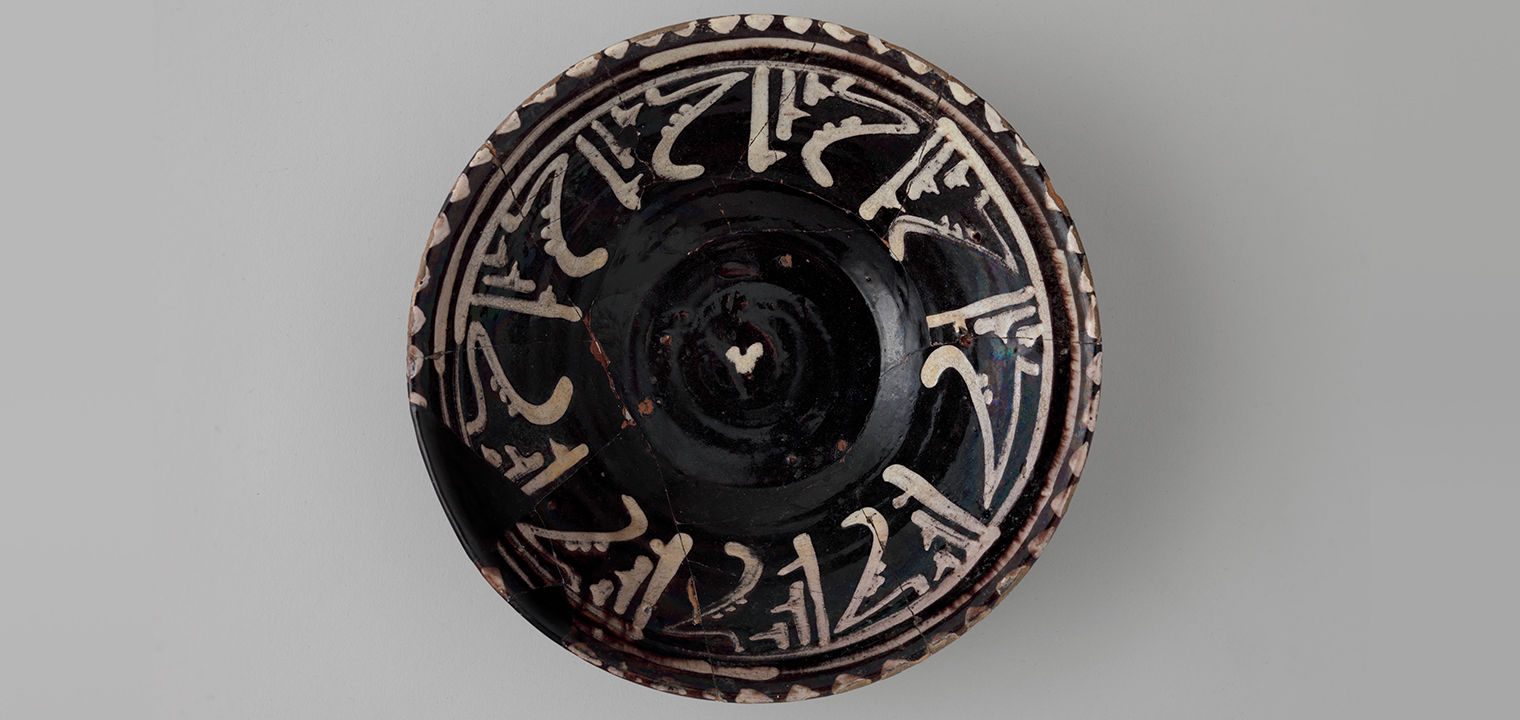 a black bowl with white calligraphy decoration around the rim 