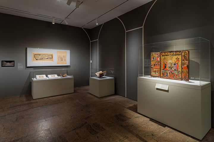 Gallery view from the Africa & Byzantium exhibition. The room is dark, with three glass exhibit cases.