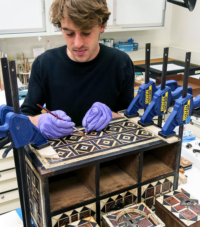 Conservation fellow stabilizes veneer on a box