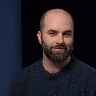 Light skinned, bald man with close trimmed beard and sweater 