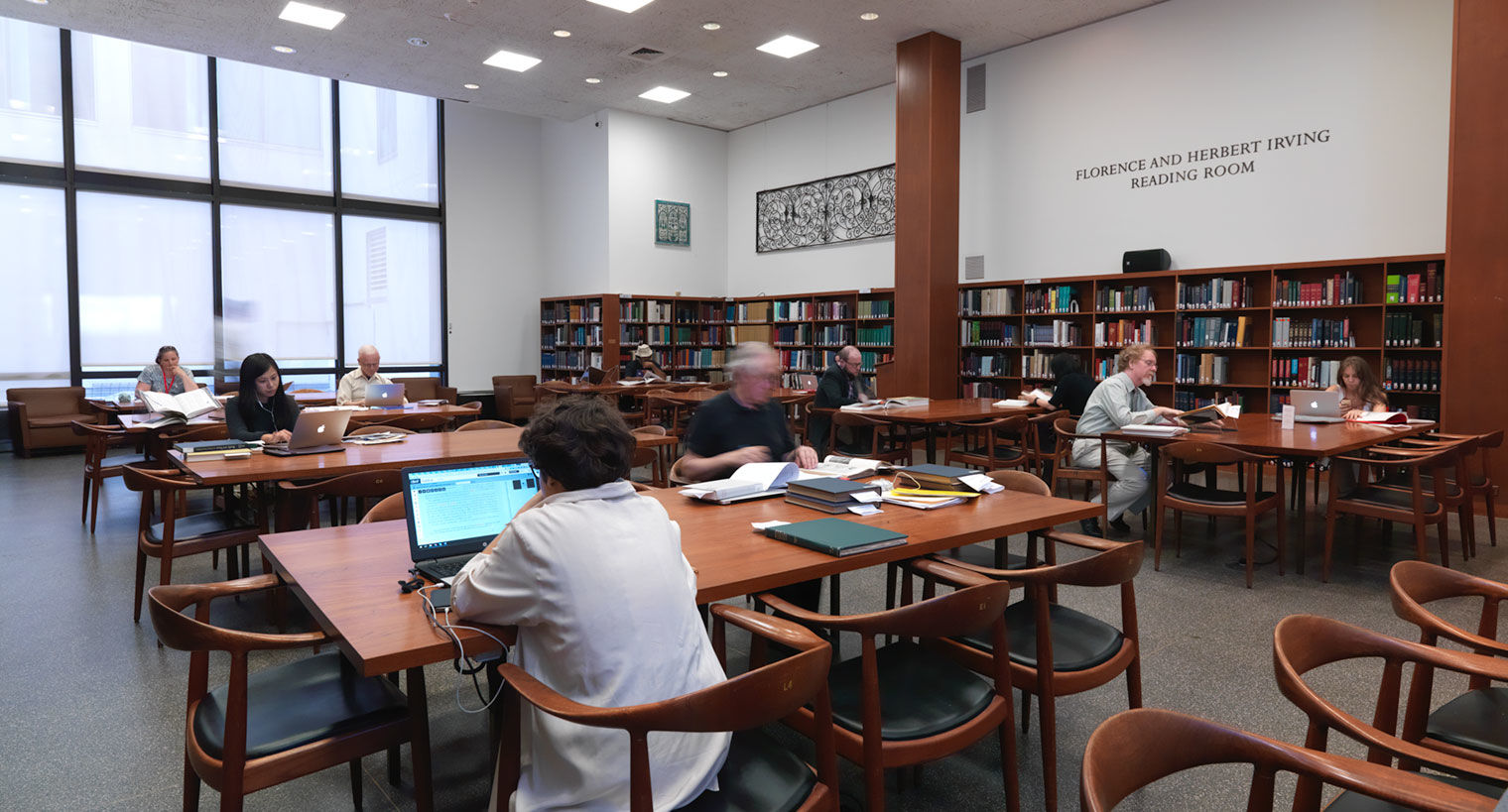 Interior view of the Florence and Irving Herbert Reading Room, showing library patrons seated at tables reading and using computers