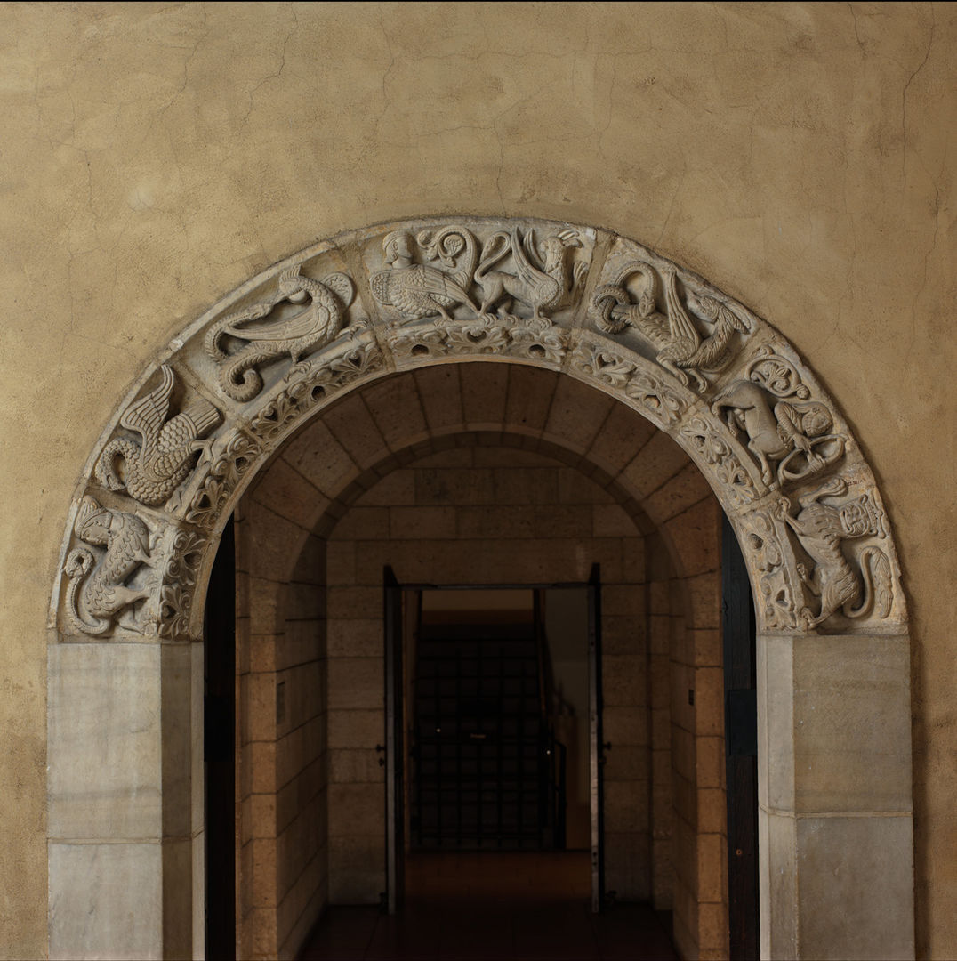A stone arched doorway with seven fantastic animals carved in relief bordering the arch