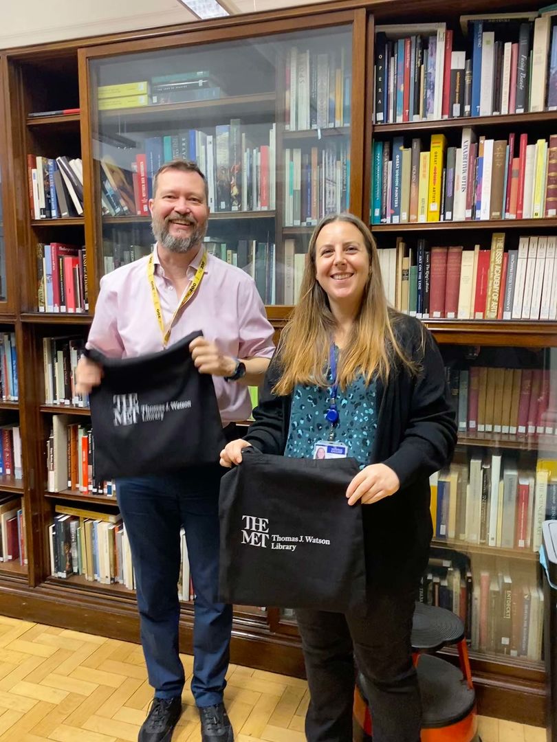 Two librarians displaying Watson Library swag