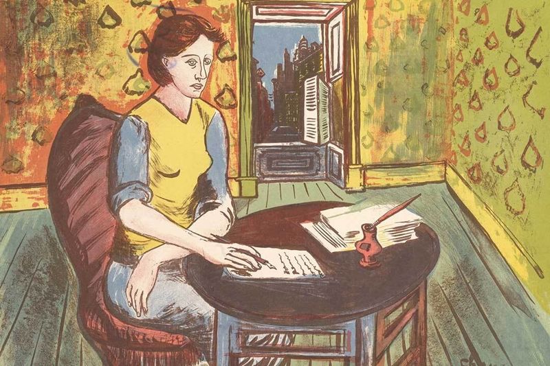 A woman sits at a table, writing