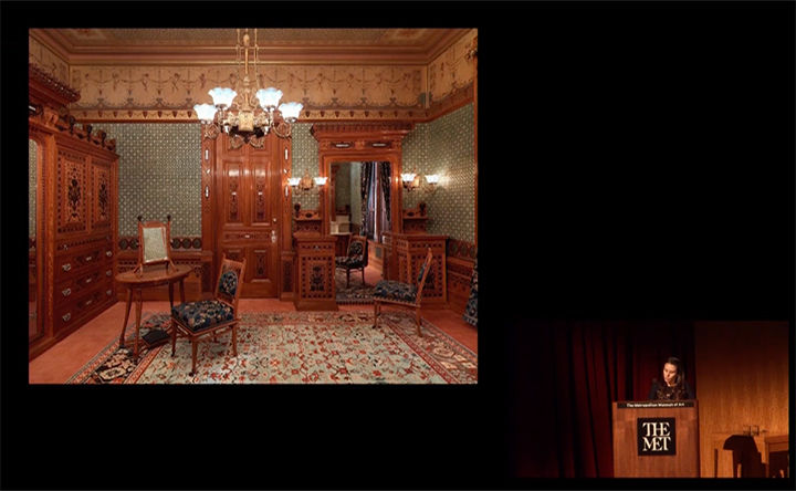 Moira Gallagher speaking at a podium with an image of the Worsham-Rockefeller Room projected alongside her.