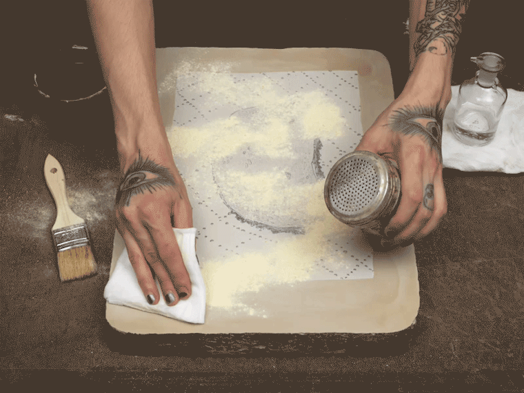 Animated image of an artist wiping rosin and talc onto a lithography stone