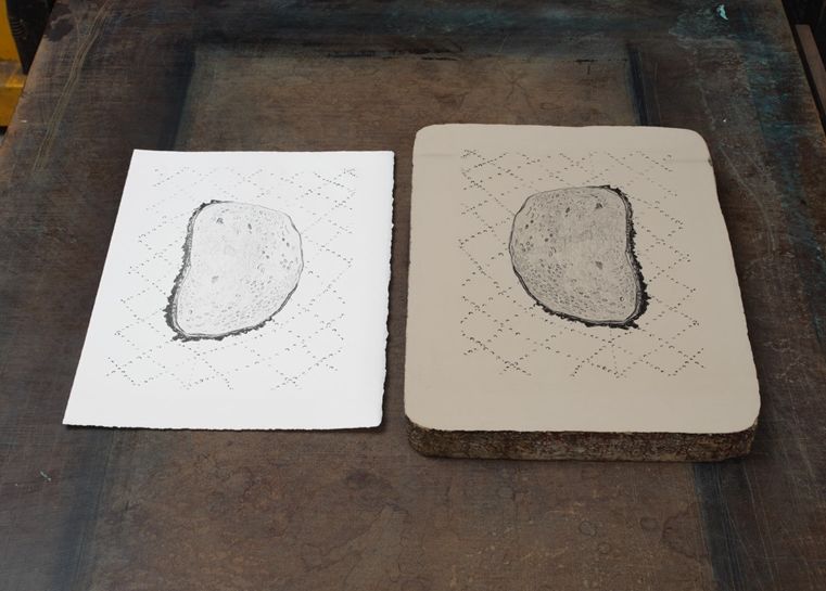 Photo of a lithography stone next to a print made with that stone