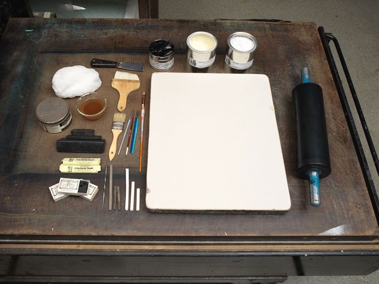 A tray of lithography tools, including a stone, crayon, water, sponge, and water
