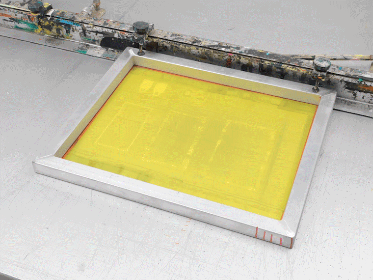 Animated image of a printmaker using a squeegee to spread ink across a screenprinting screen, and then printing the design on paper
