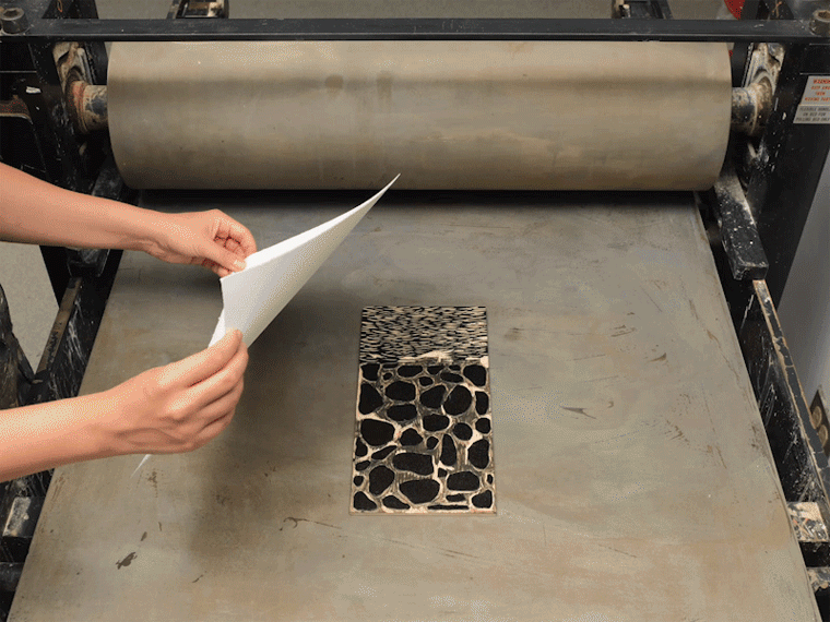 Animated image of a woodblock print being made in a printing press