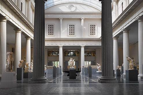 A very large gallery enclosed by a colonnade and filled with with sculptures from ancient Rome