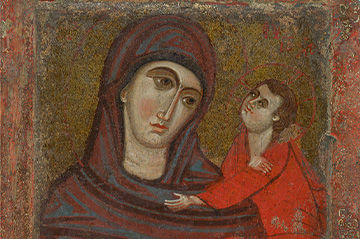An ancient religious icon depicting the virgin mary in a dark blue mantle with a red robe, gazing solemnly while holding the child jesus, who wears a red garment and touches her chin affectionately.
