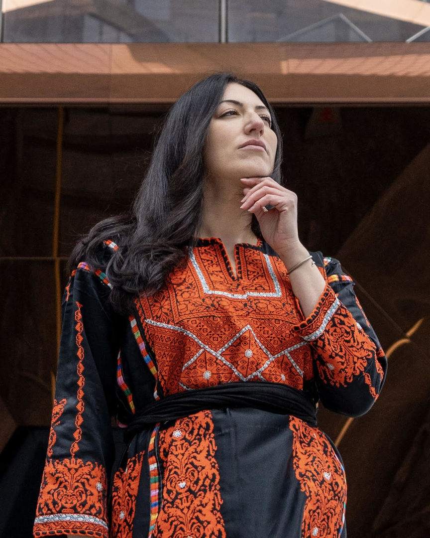 Woman wearing a black and red Palestinian embroidered dress