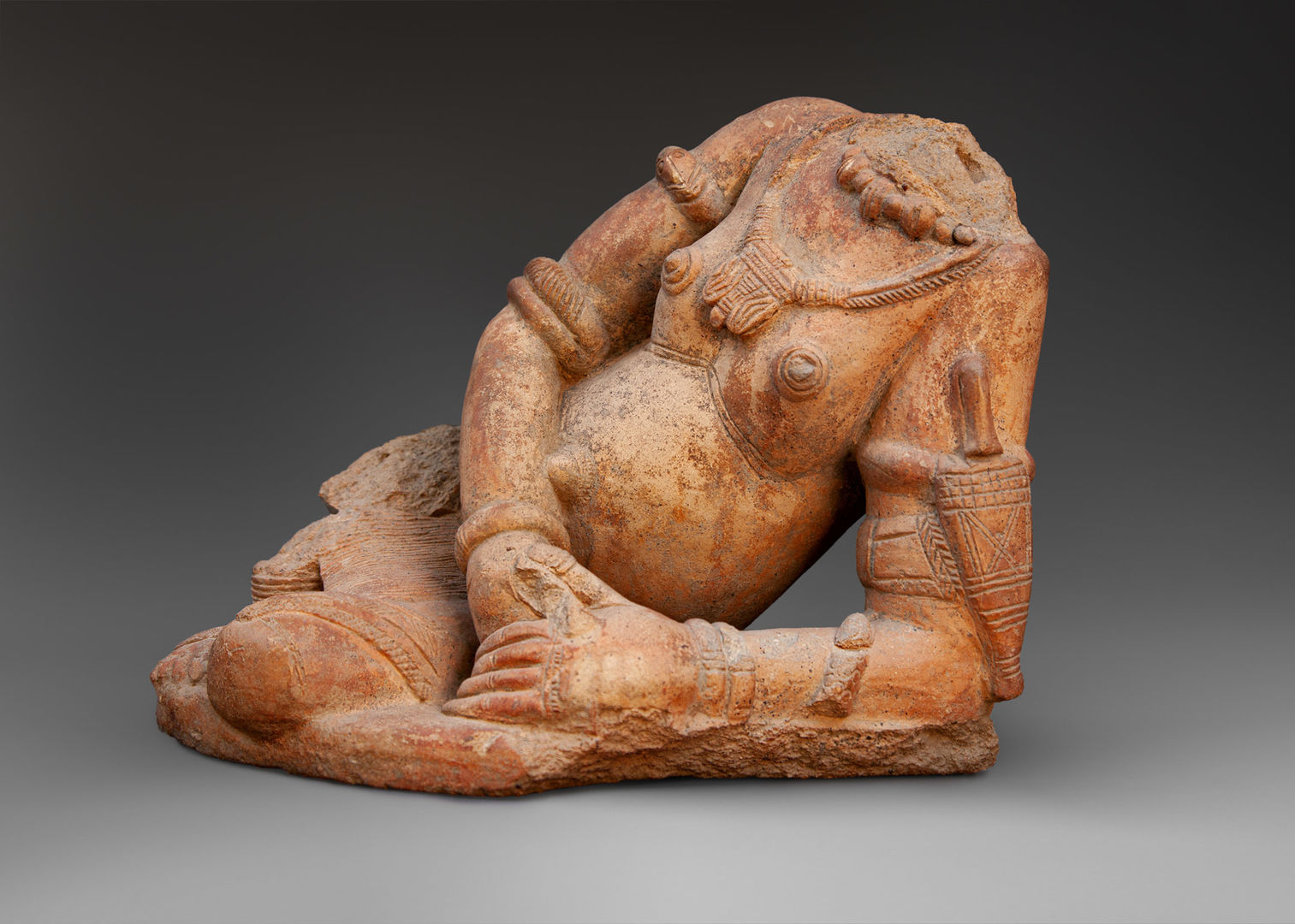 A terracotta figurine of a reclining nude woman