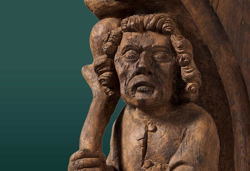 Detail of a medieval wooden architectural support with a peasant holding a club