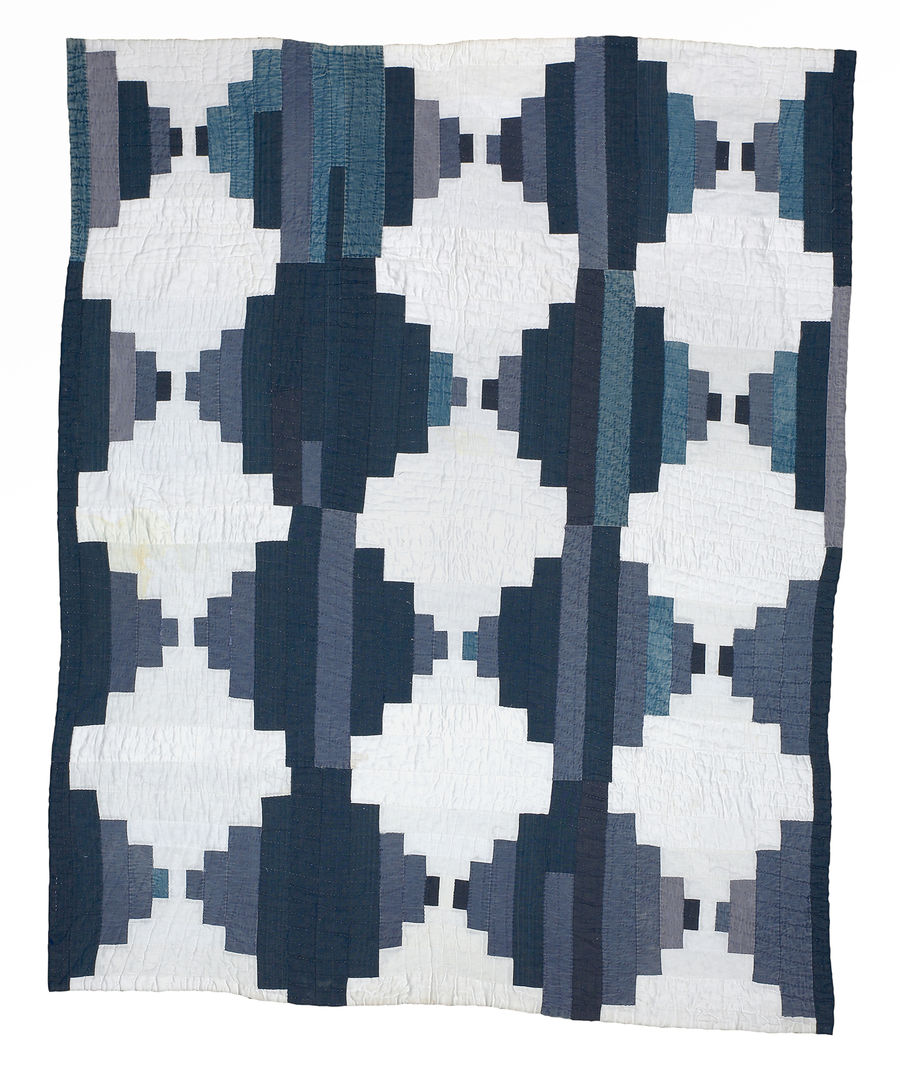 White quilt with geometric patterns made up of strips of blue.