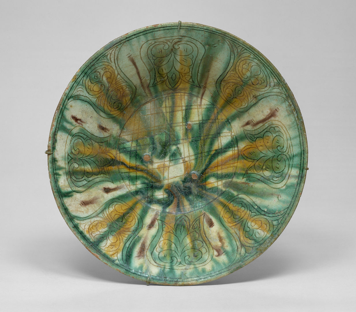 Bowl with geometric and floral patterns, glazed in green, yellow, and brown.