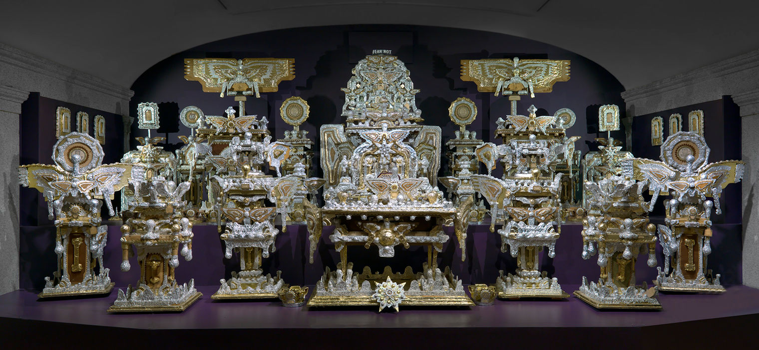 Elaborate artwork with a throne in the background, surrounded by religious-inspired objects. All of the objects shine in golds and silvers.